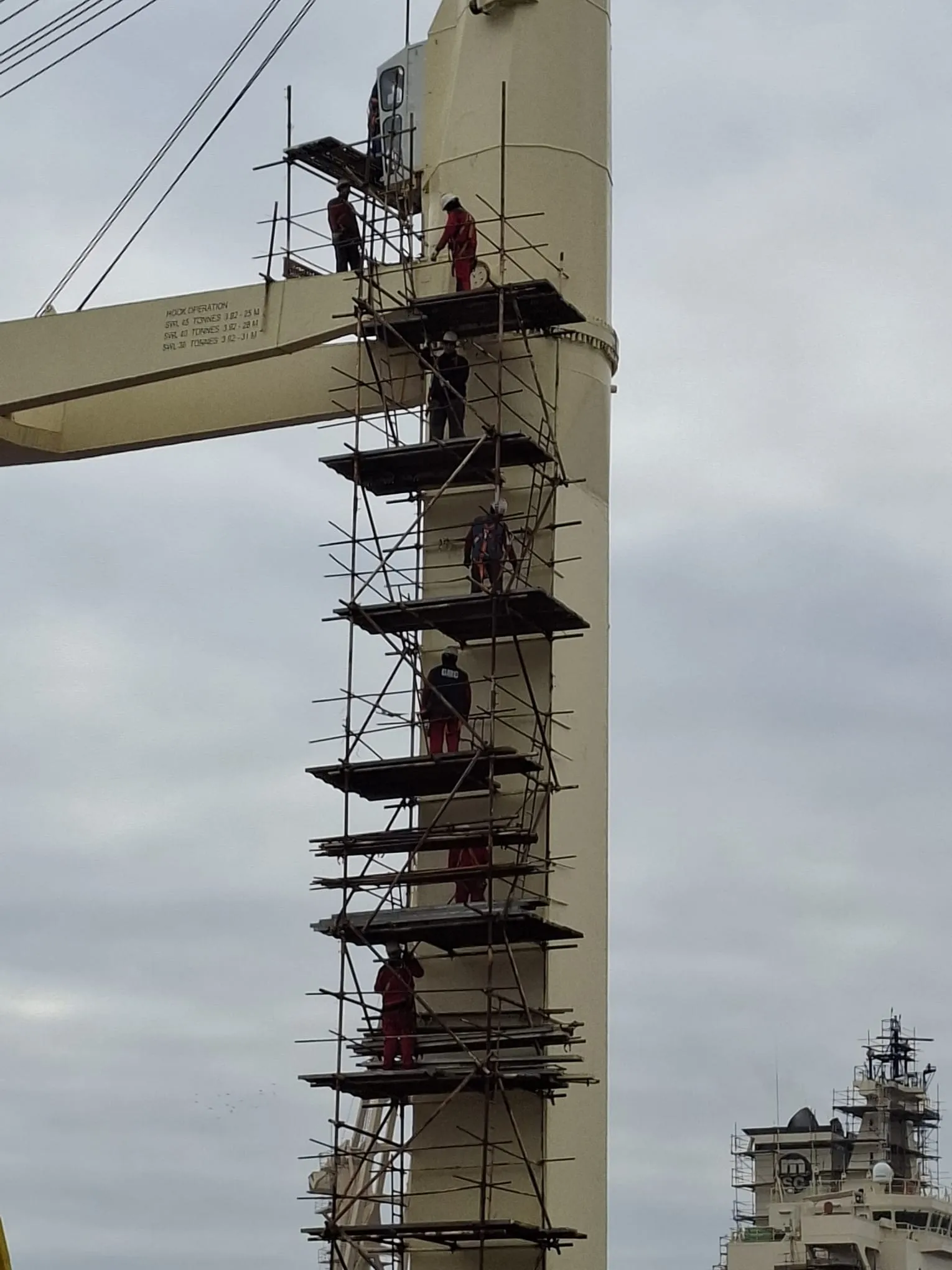 Omega Junior scaffolders working at height on a vessel crane